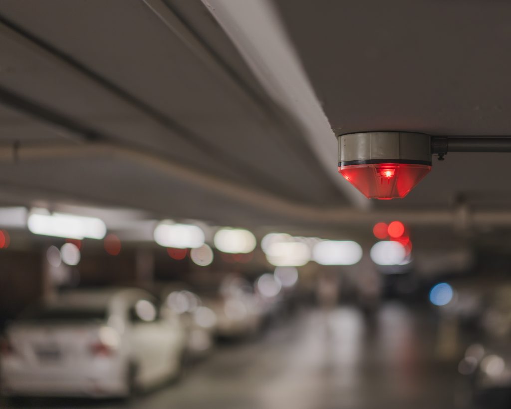 A red car park signal light indicating availability status in a dimly lit underground parking garagecar-park-signal-red-light