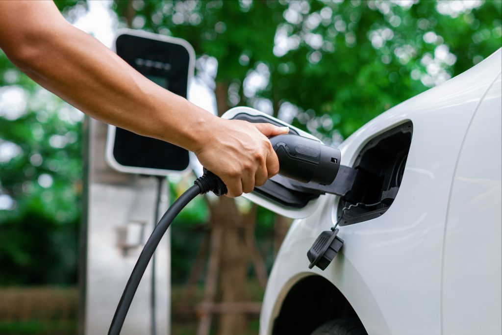 Close-up of a person plugging in a charger to an electric vehicle at an EV car charging station installation/electric car charging station installation.